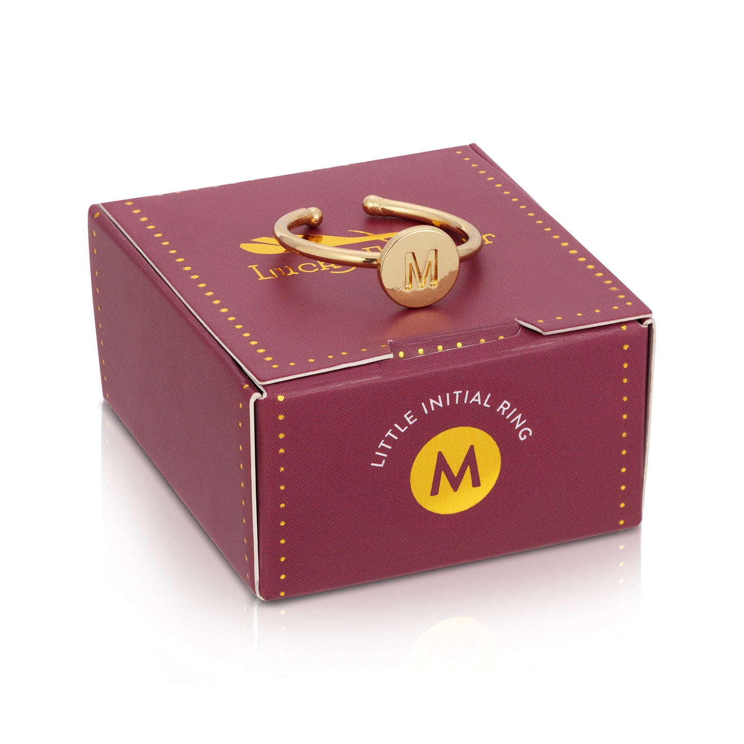 A gold-colored ring with the letter M rests on top of a maroon box labeled "LITTLE INITIAL RING".