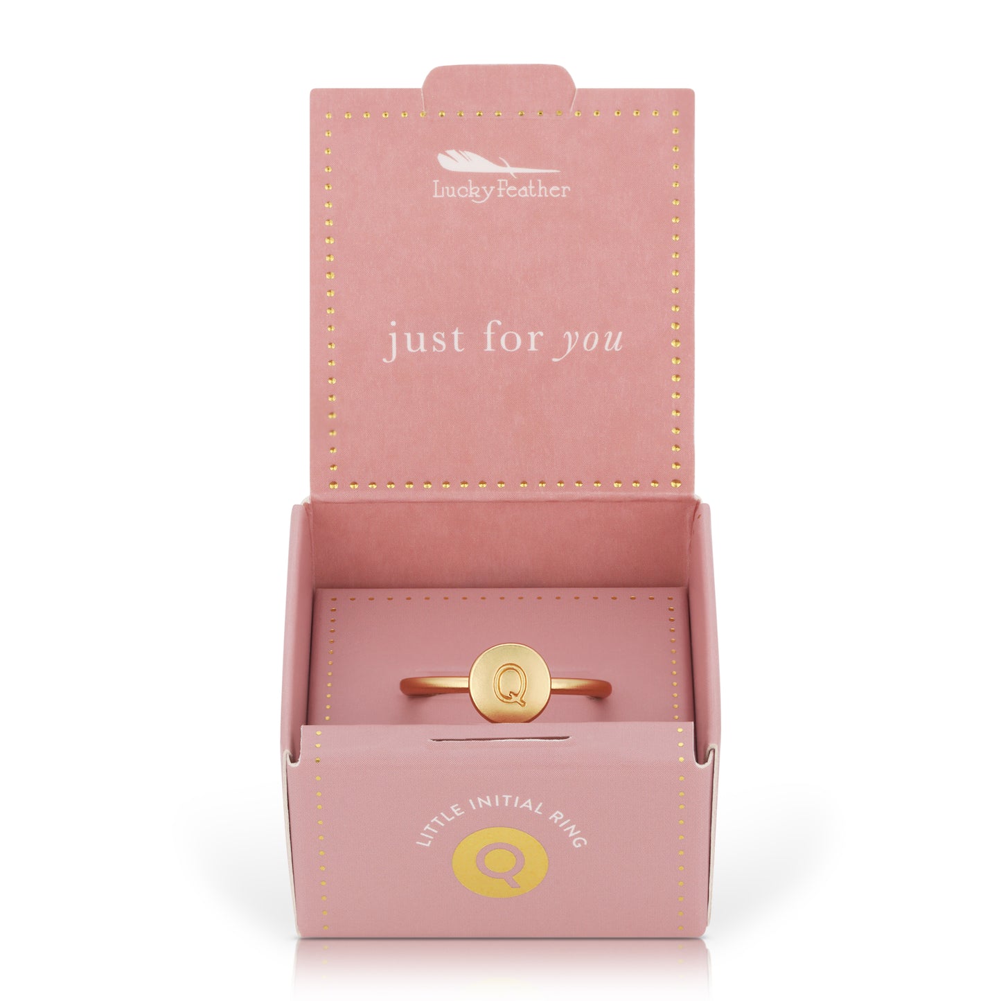 A gold ring with the letter "Q" in a pink gift box labeled "Lucky Feather" and "Little Initial Ring."