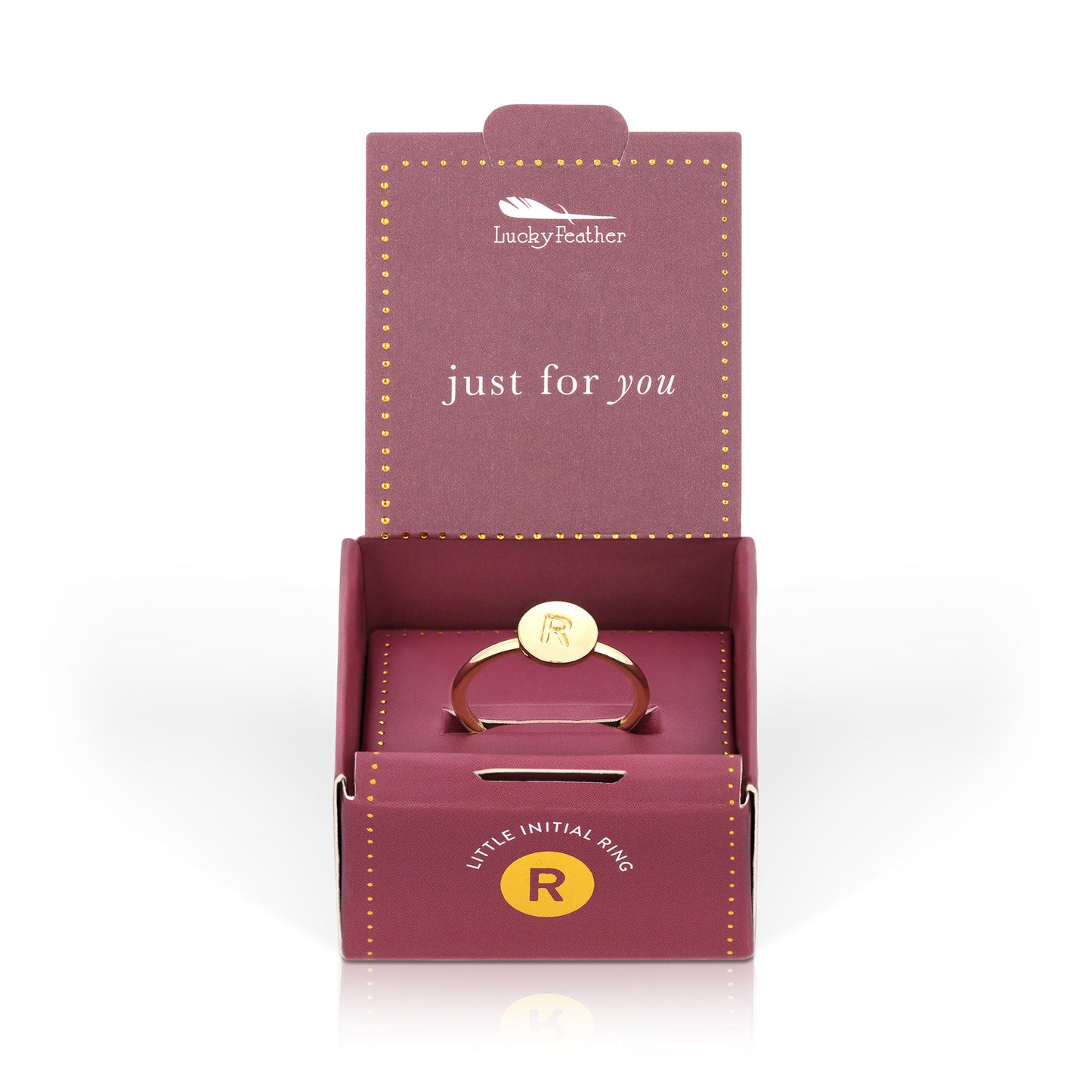 A gold-colored ring with the letter R is in a "Lucky Feather" jewelry box.