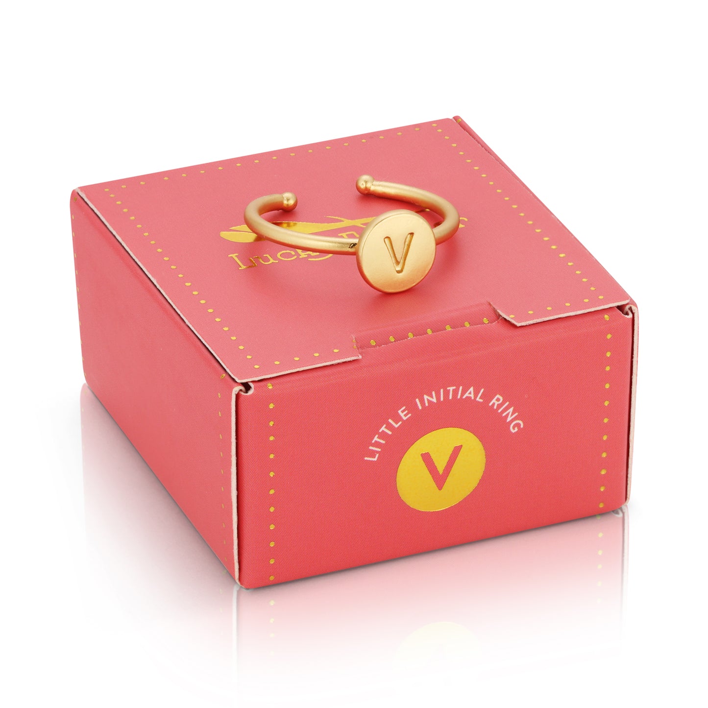 A gold-colored ring with the letter "V" rests on a pink box labeled "LITTLE INITIAL RING".