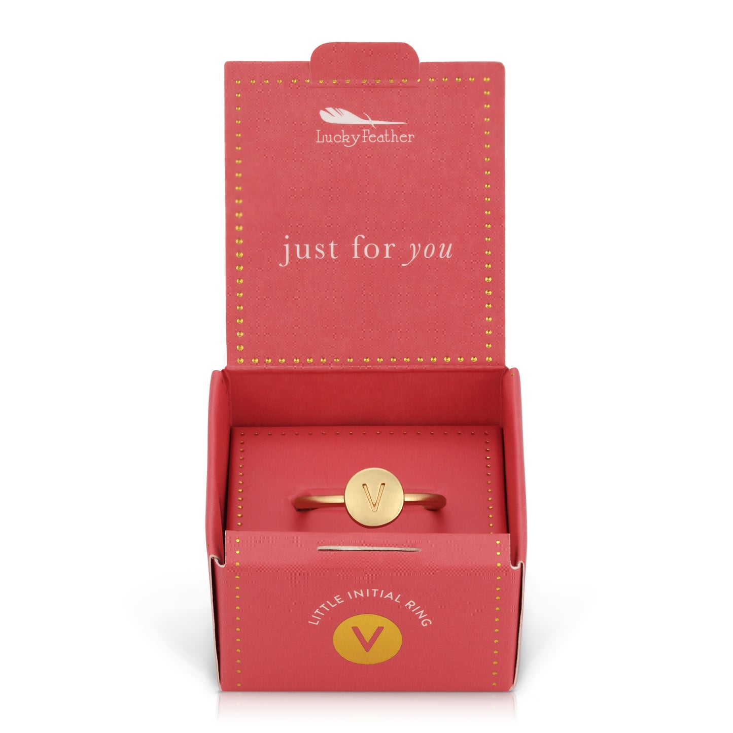 A gold-colored ring with the letter "V" is displayed in an open, pink gift box.