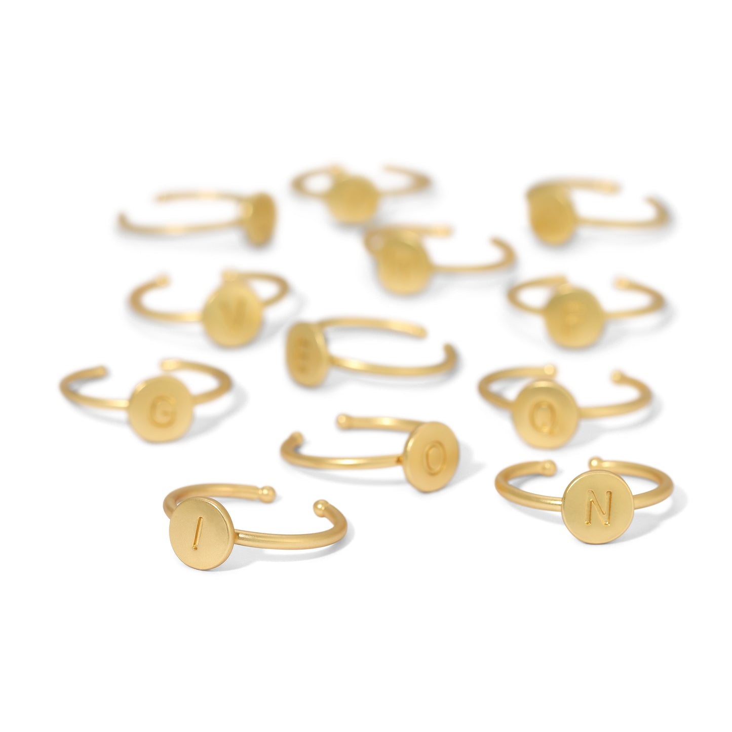 Several gold rings, each featuring a circular design engraved with a different letter of the alphabet.