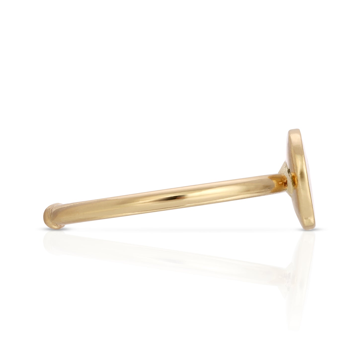 A gold ring with a flat, round head lies on a reflective white surface.