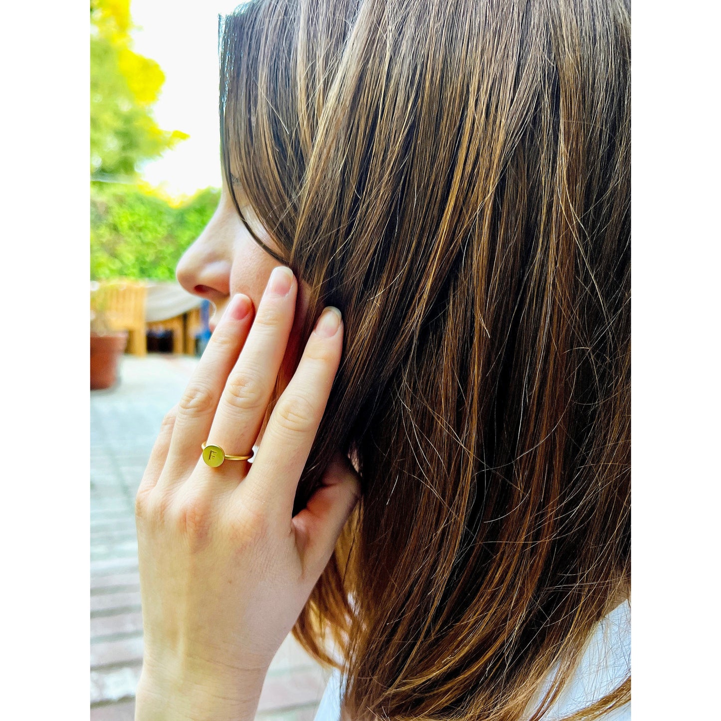 Person's profile with a gold ring that has the letter F.