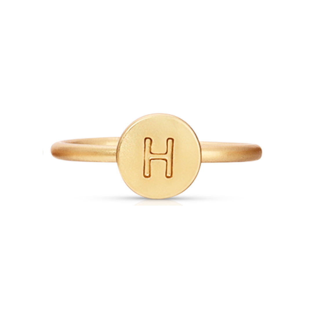 A gold ring with the letter H engraved on a circular face.