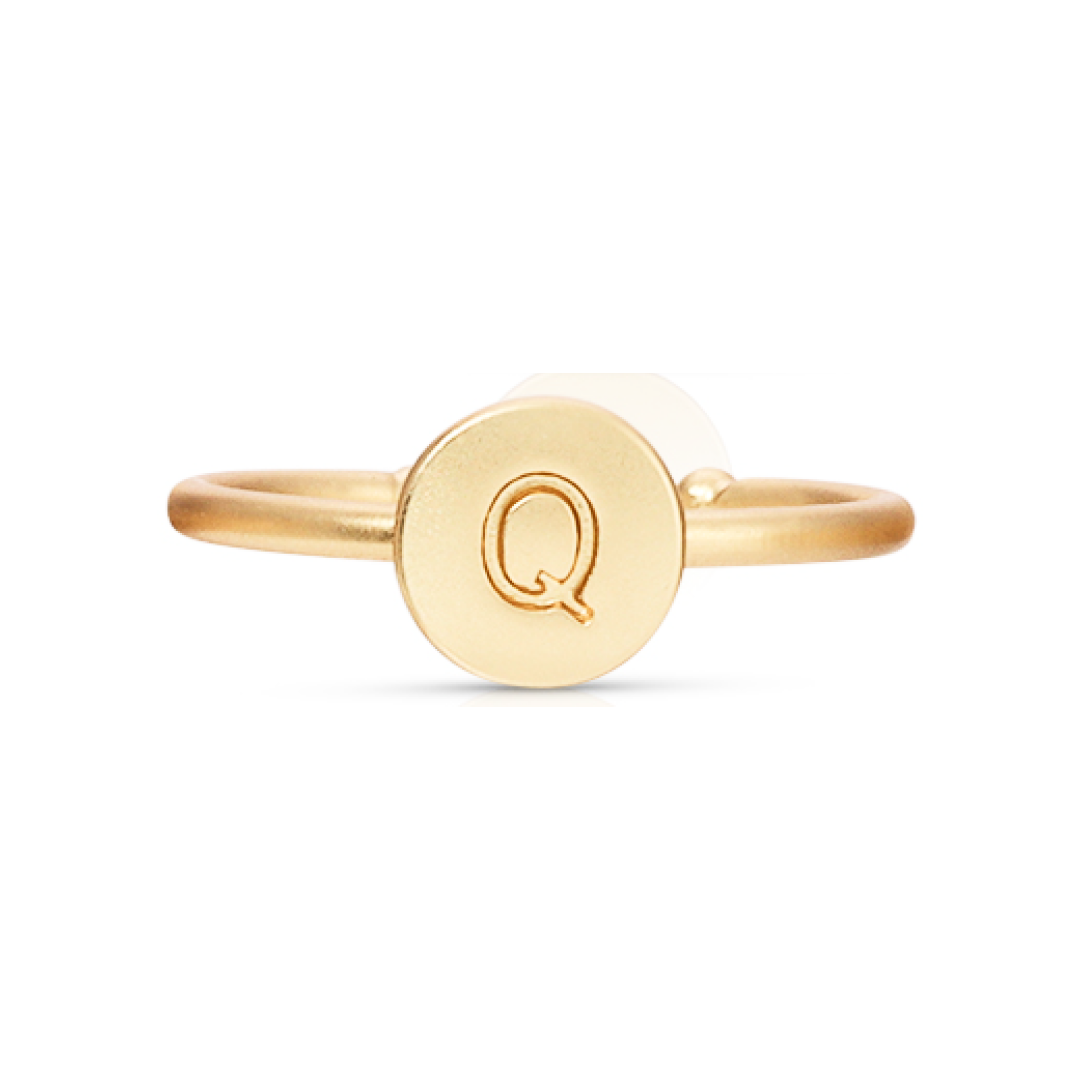 A gold ring with a circular face bearing the letter Q.