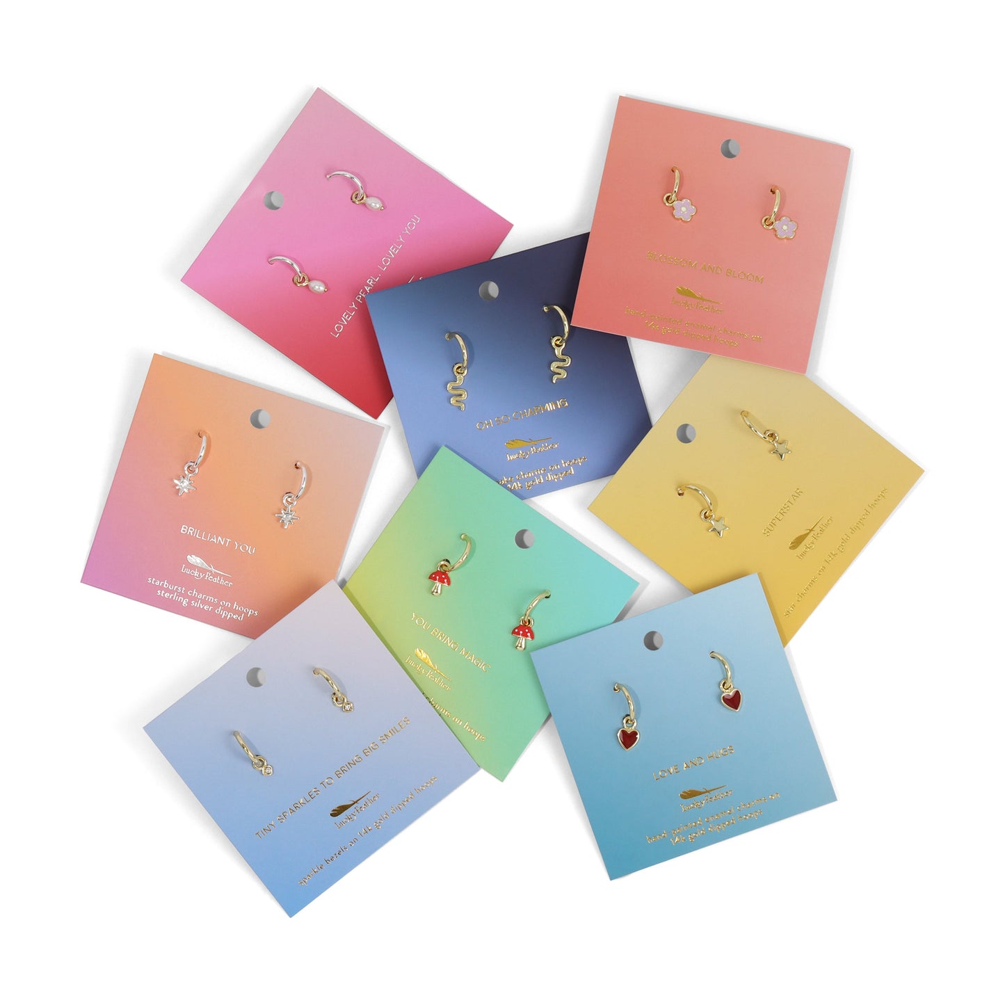 Various earring sets with charms on pastel-colored cards are arranged on a white background.