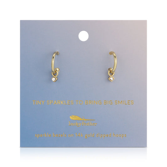 A pair of gold hoop earrings with diamond charms, displayed on a blue card with gold text.