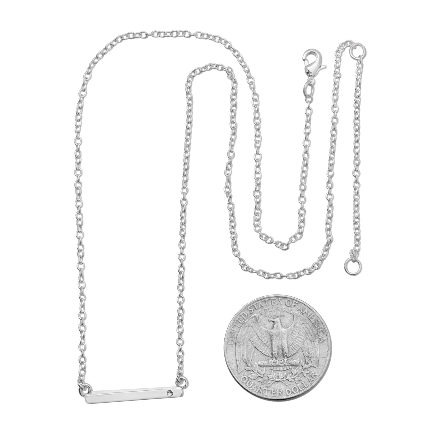 A silver chain necklace with a bar pendant is displayed next to a quarter coin.
