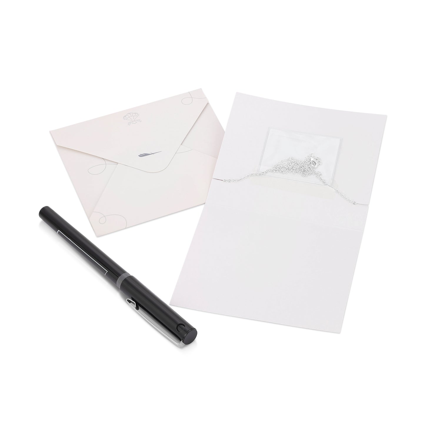 The image shows two envelopes, a necklace partially visible in one, and a black pen on a white surface.