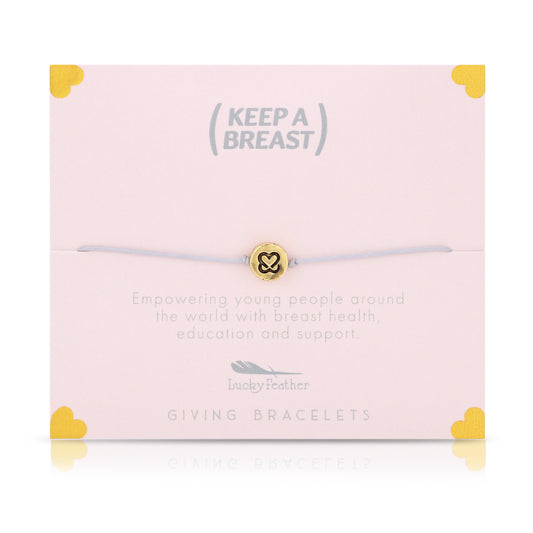 A bracelet with a gold charm sits on a pink card with the text "Keep A Breast," along with details on breast health education and support.