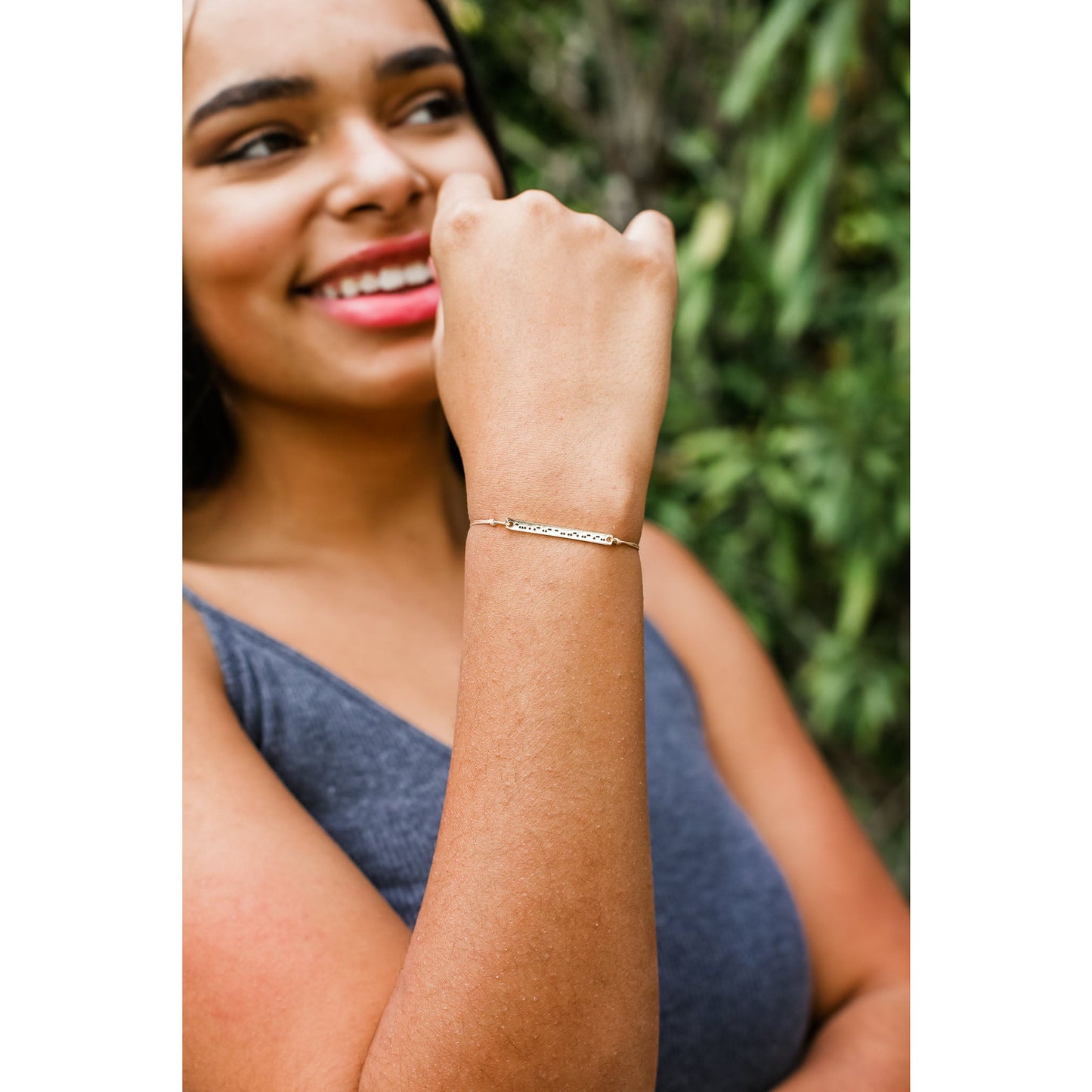 A person wears a bracelet with dots and dashes on their wrist.