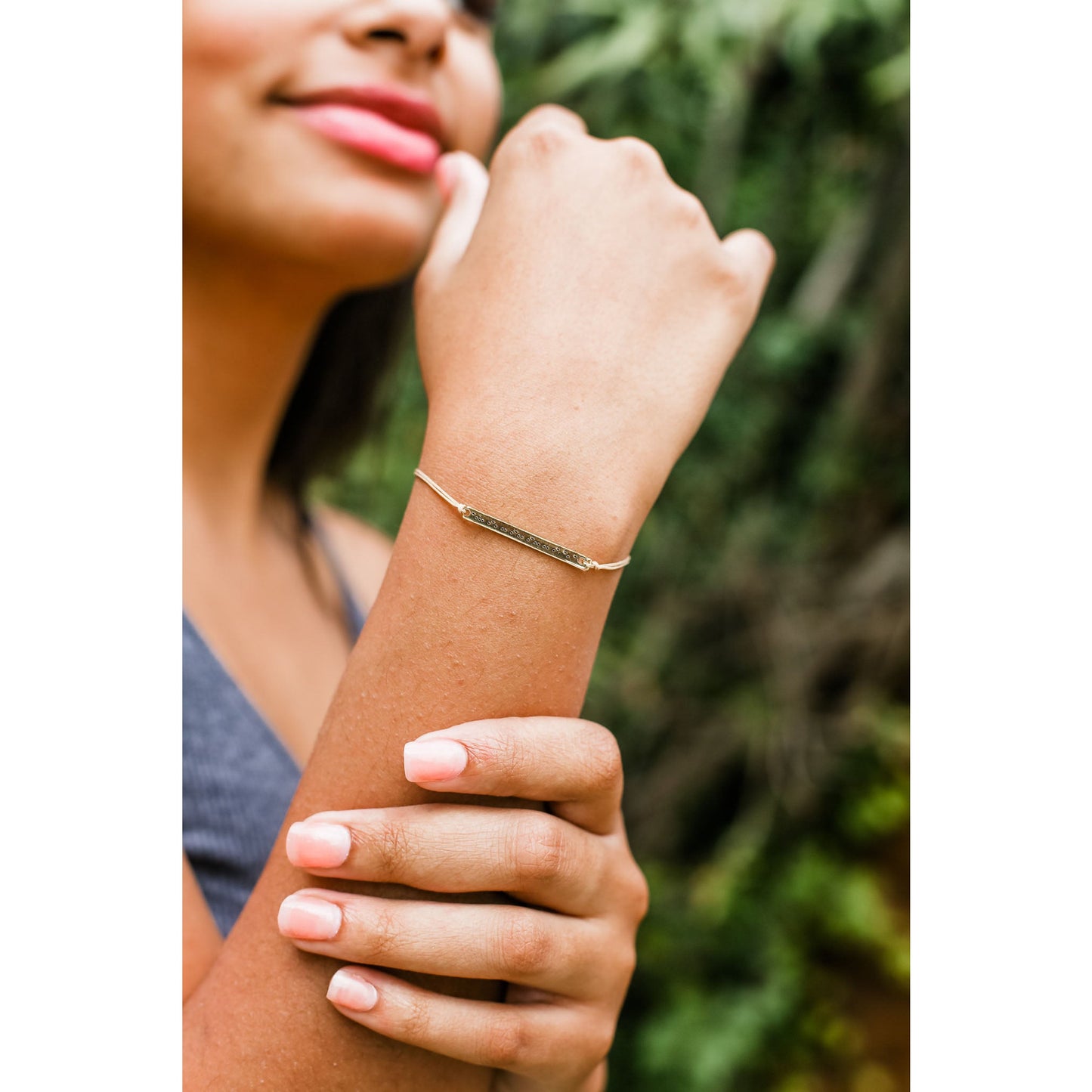 A woman wears a gold-colored bracelet with raised dots.