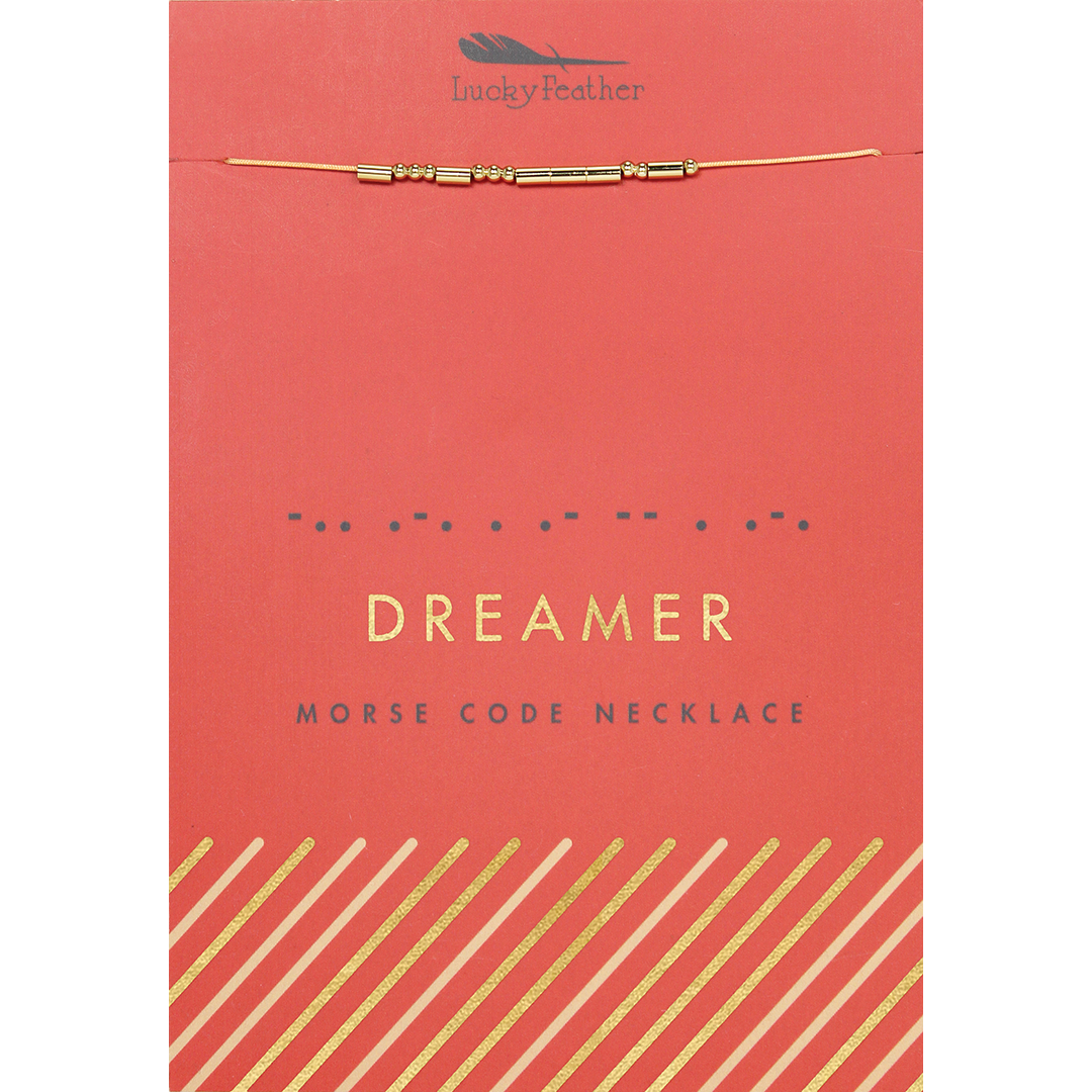 A "Lucky Feather" brand Morse code necklace that spells out "Dreamer" on a coral-colored card.