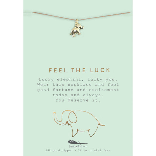 A lucky elephant necklace hangs on a card with the words "Feel the Luck."