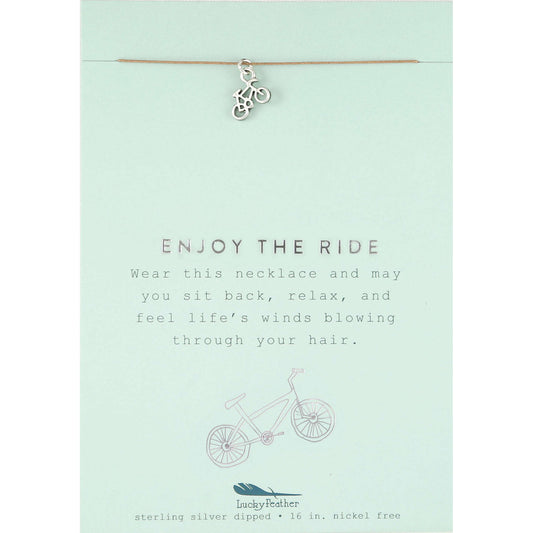 A "Lucky Feather" necklace with a bicycle charm on a card that reads "Enjoy the Ride."
