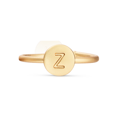 A gold-colored ring featuring a round face with the letter Z engraved on it.